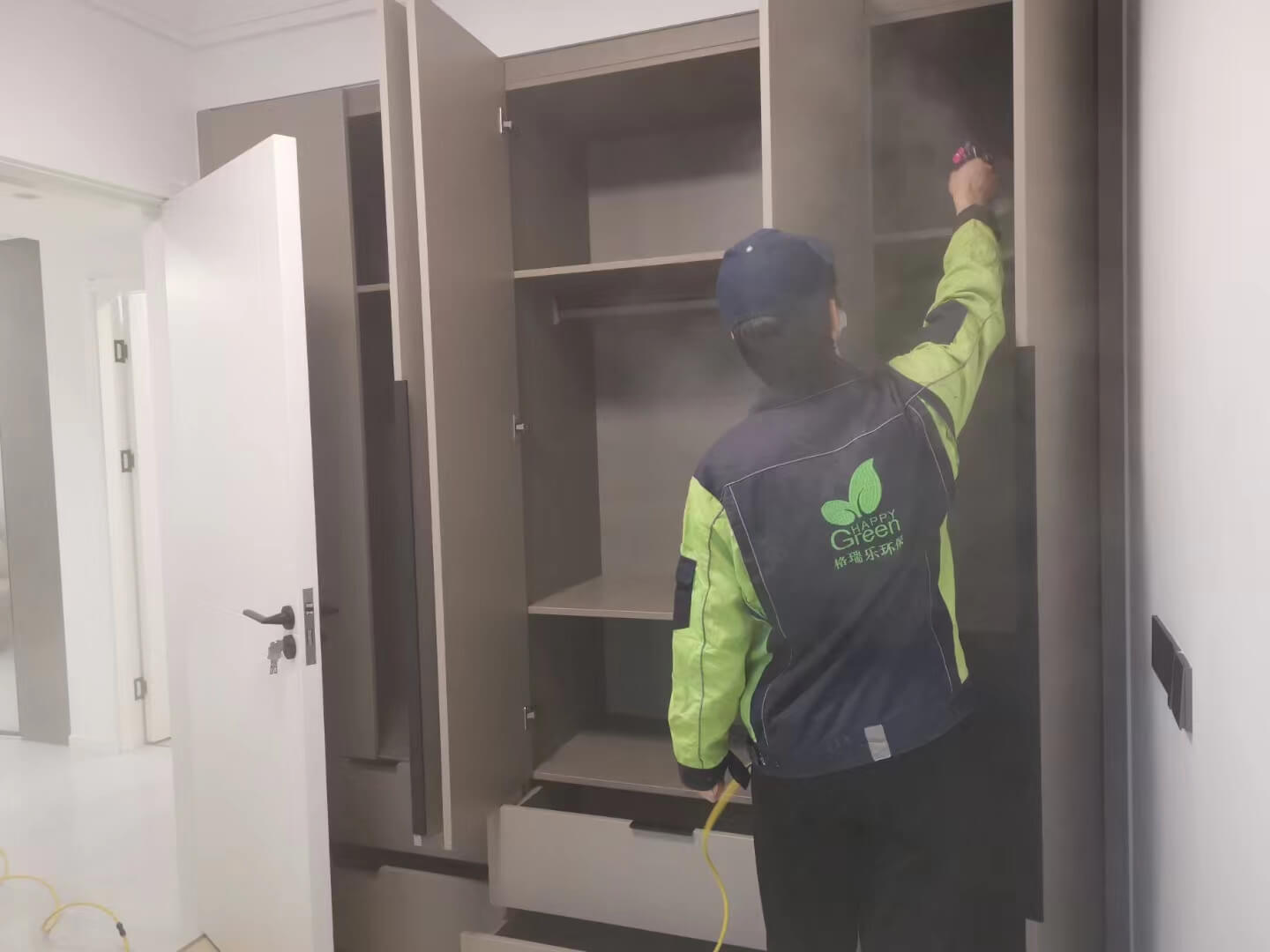 客厅电视背景墙安装现场，工人用湿布蘸取格瑞乐除甲醛清洁液，认真擦拭木质装饰板。