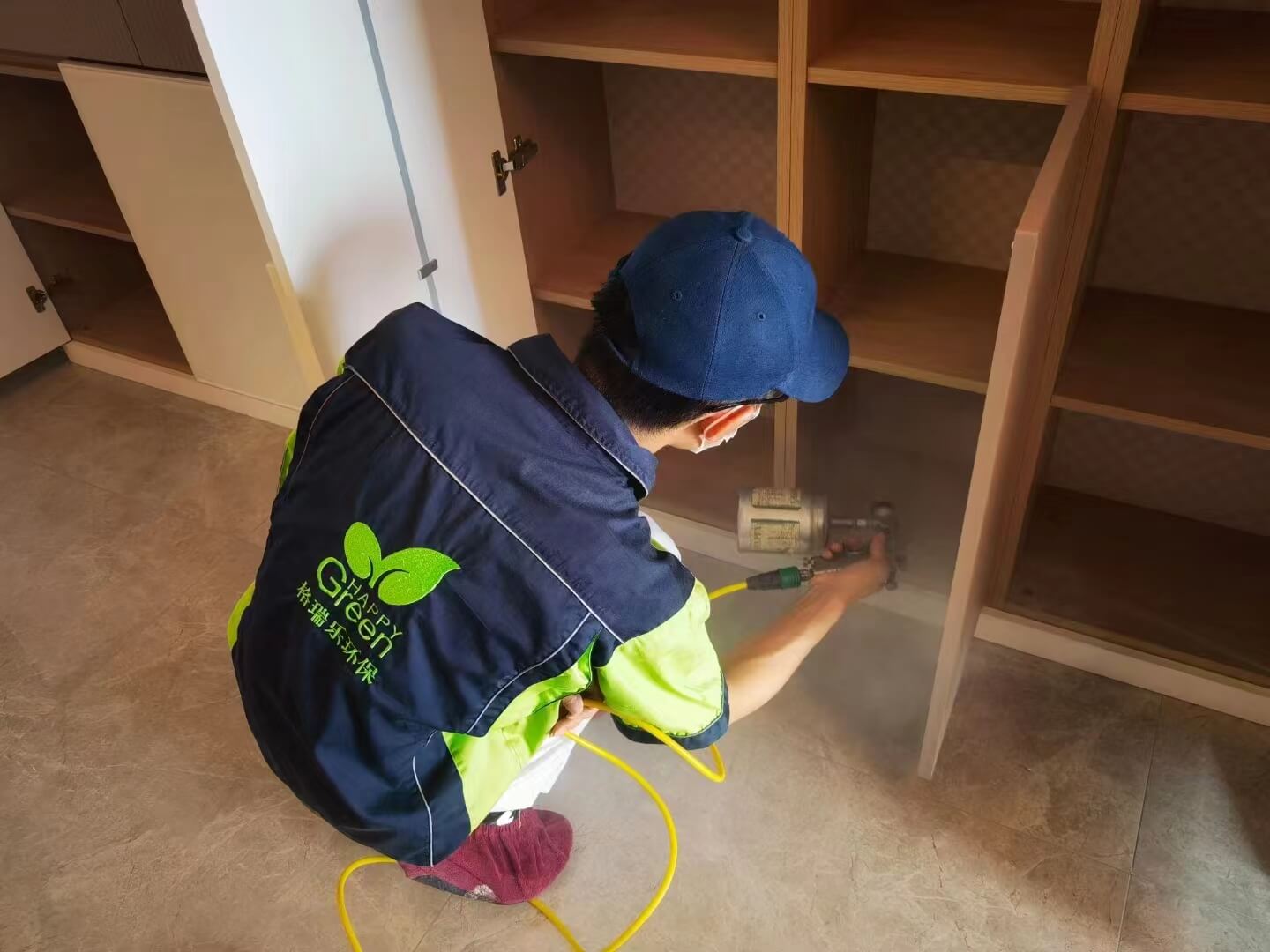 展示新房走廊的鞋柜，工人在鞋柜的底部与层板角落粘贴格瑞乐除甲醛纳米矿晶吸附片。