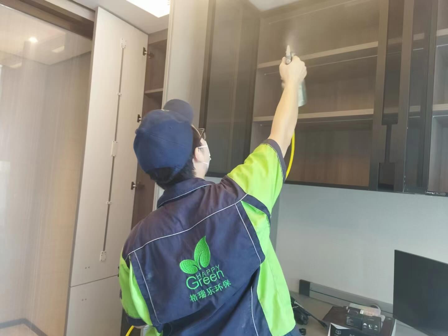 客厅电视柜安装现场，工人用湿布蘸取格瑞乐除甲醛清洁液，认真擦拭电视柜的抽屉轨道。